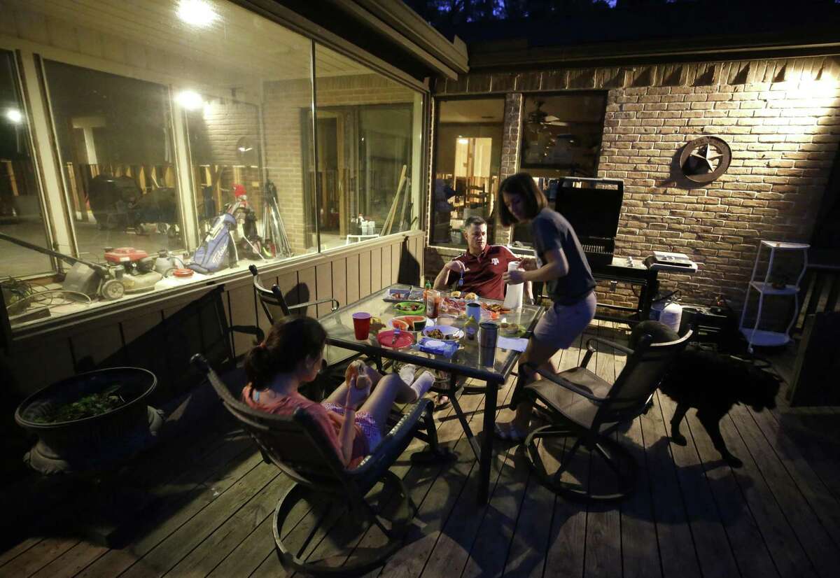 Chloe Coulter, 11, left, sits with her parents Chris Coulter and Jennifer Coulter and the family dog, Max, as they eat dinner outside their flooded Kingwood home Wednesday, Feb. 28, 2018. They are living in a travel trailer in the driveway of their home while waiting for their house to be rebuilt after flooding from Hurricane Harvey.