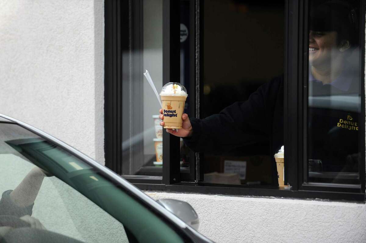 An employee hands an iced coffee to a customer from the drive-through window at the new Donut Delight store at 2720 Summer St., in Stamford, Conn. Photographed on Thursday, March 1, 2018.