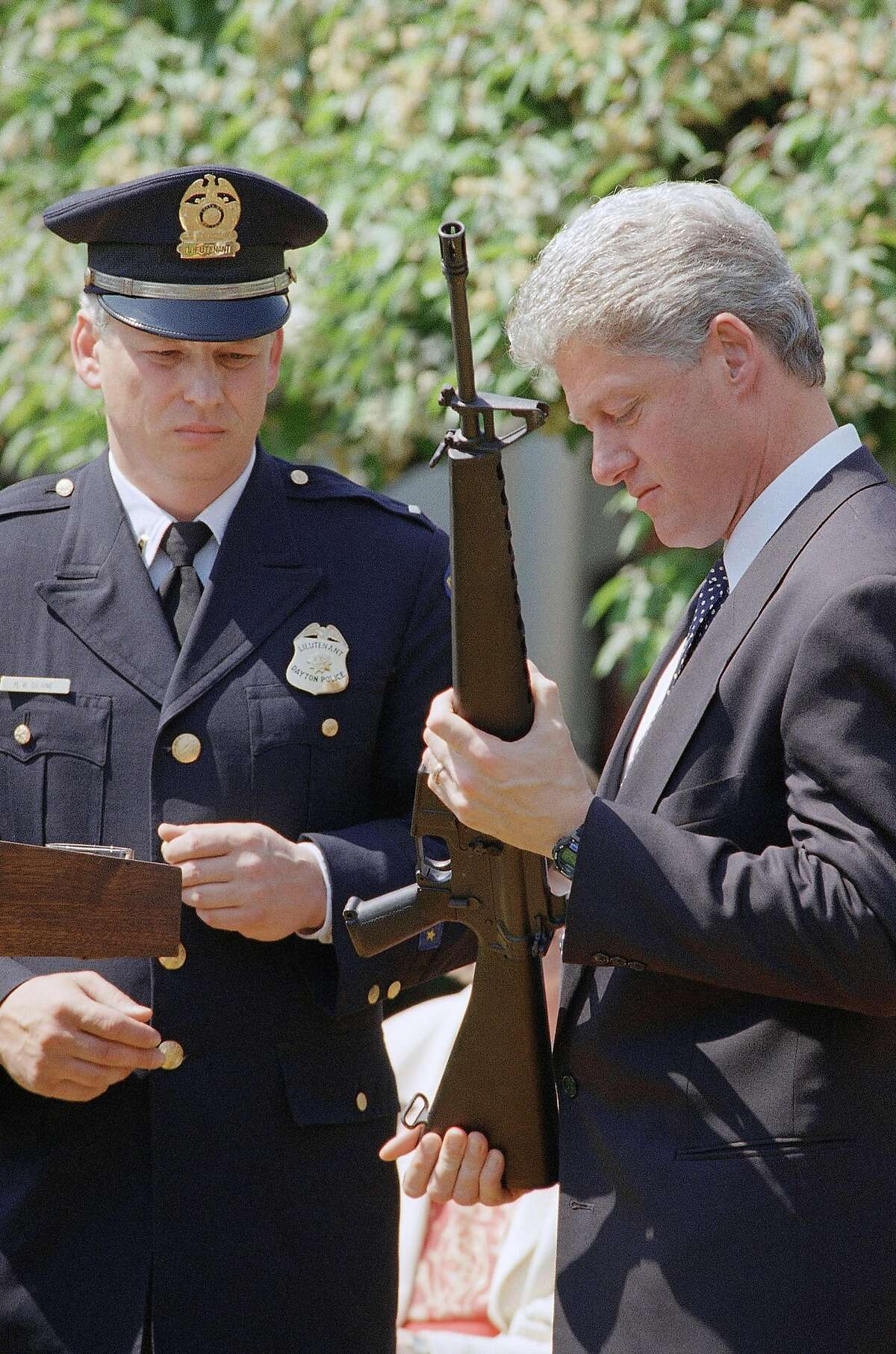 President Bill Clinton holds a Colt AR-15 rifle during a ceremony in the Rose Garden of the White House in Washington, April 25, 1994 where he launched efforts to pass the assault weapons ban. Dayton, Ohio Police Lt. Randy Bean, whose fellow officer Steve Whalen was gunned down with an AR-15 in 1991, looks on at left. (AP Photo/Dennis Cook)