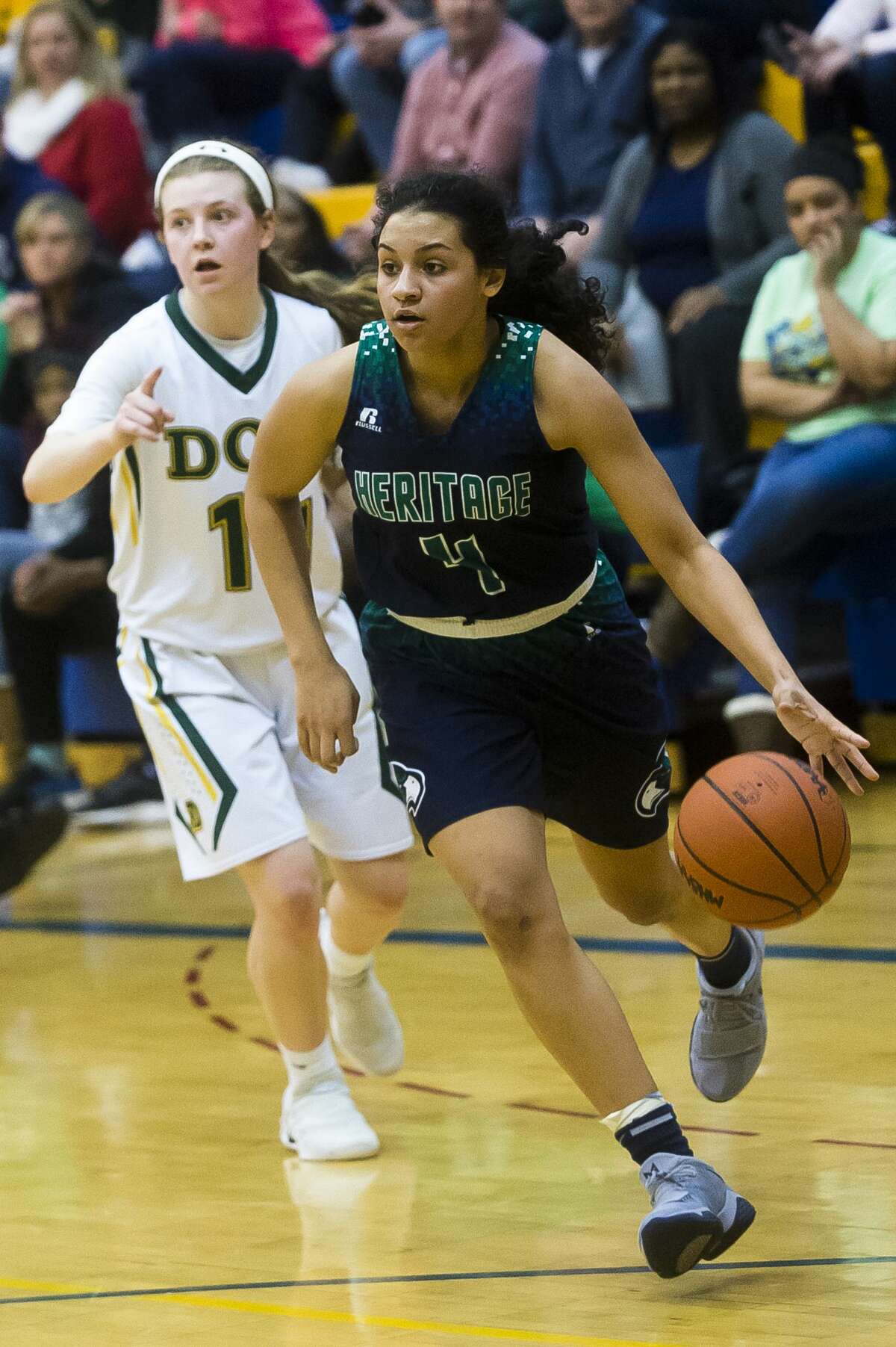 Saginaw Heritage junior Moira Joiner dribbles toward the basket as Dow junior Molly Davis follows behind her their district finals game on Friday at Midland High School. (Katy Kildee/kkildee@mdn.net)