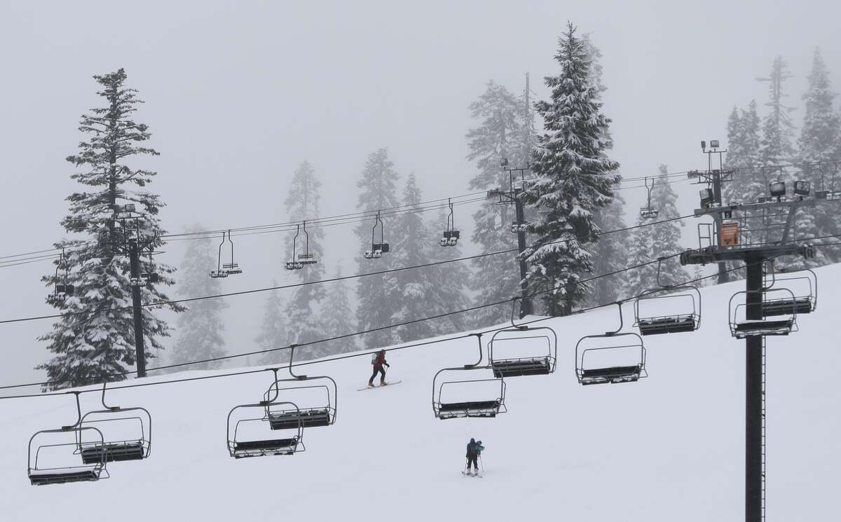 Skiers make their way uphill under idle lift chairs at the Summit at Snoqualmie Ski Area as fresh snow falls, Wednesday, Feb. 14, 2018, in Snoqualmie Pass, Wash.