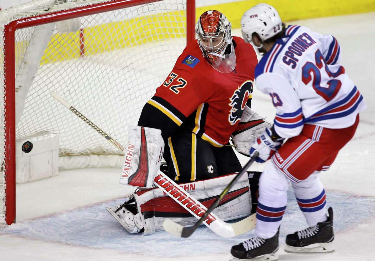 New York Rangers' Ryan Spooner, right, scores against Calgary Flames goalie Jon Gillies during second-period NHL hockey game action in Calgary, Alberta, Friday, March 2, 2018. (Larry MacDougal/The Canadian Press via AP)