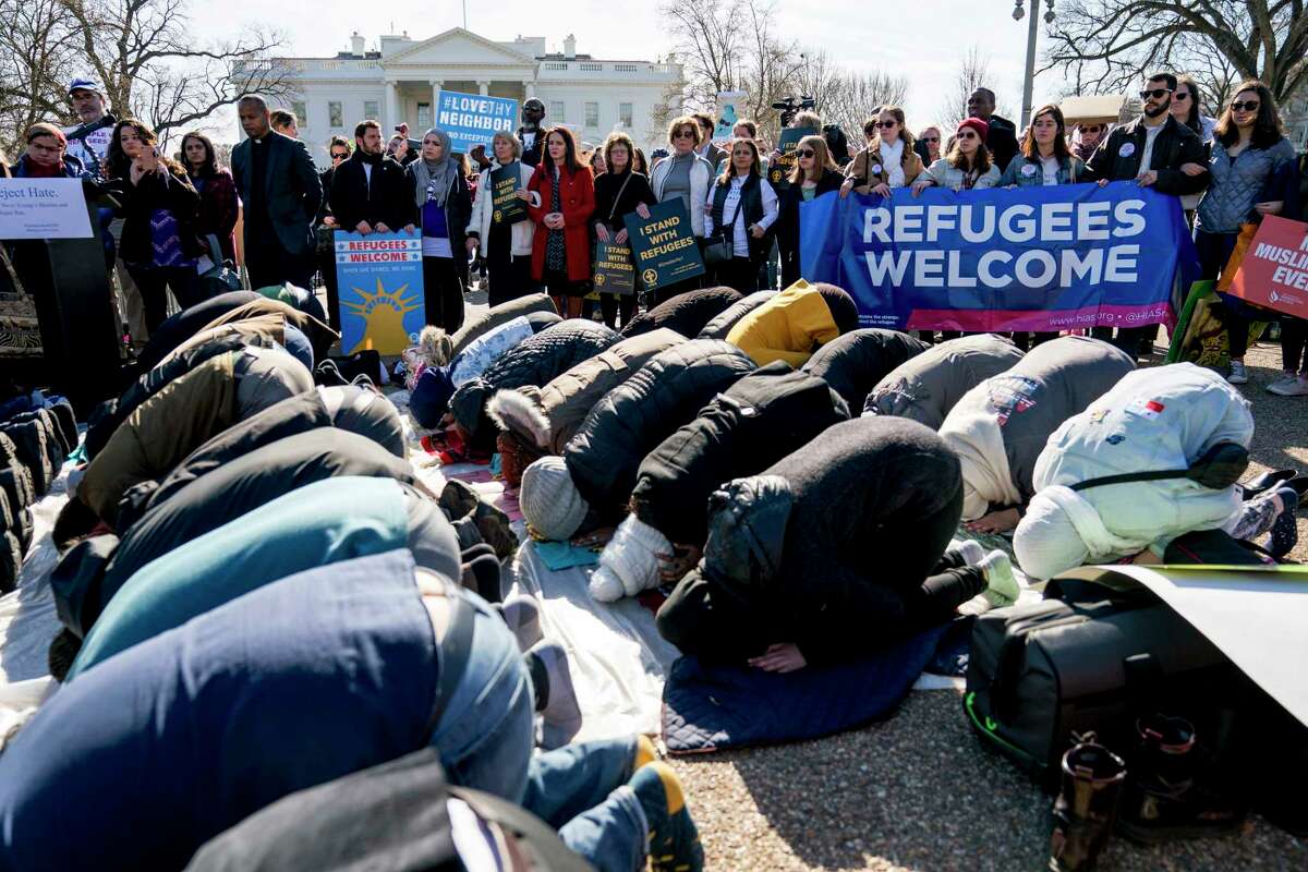 Supporters surround a group who perform the Islamic midday prayer outside the White House during a rally on the one-year anniversary of the Trump Administration's first partial travel ban.