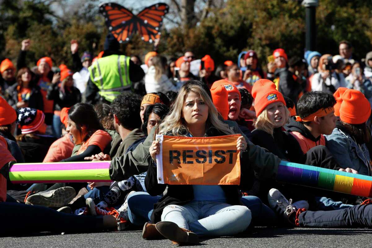 A woman holds up a sign that says, "resist," as supporters of the Deferred Action for Childhood Arrivals (DACA) block an intersection near the U.S. Capitol as an act of civil disobedience in support of DACA recipients, Monday, March 5, 2018, on Capitol Hill in Washington.