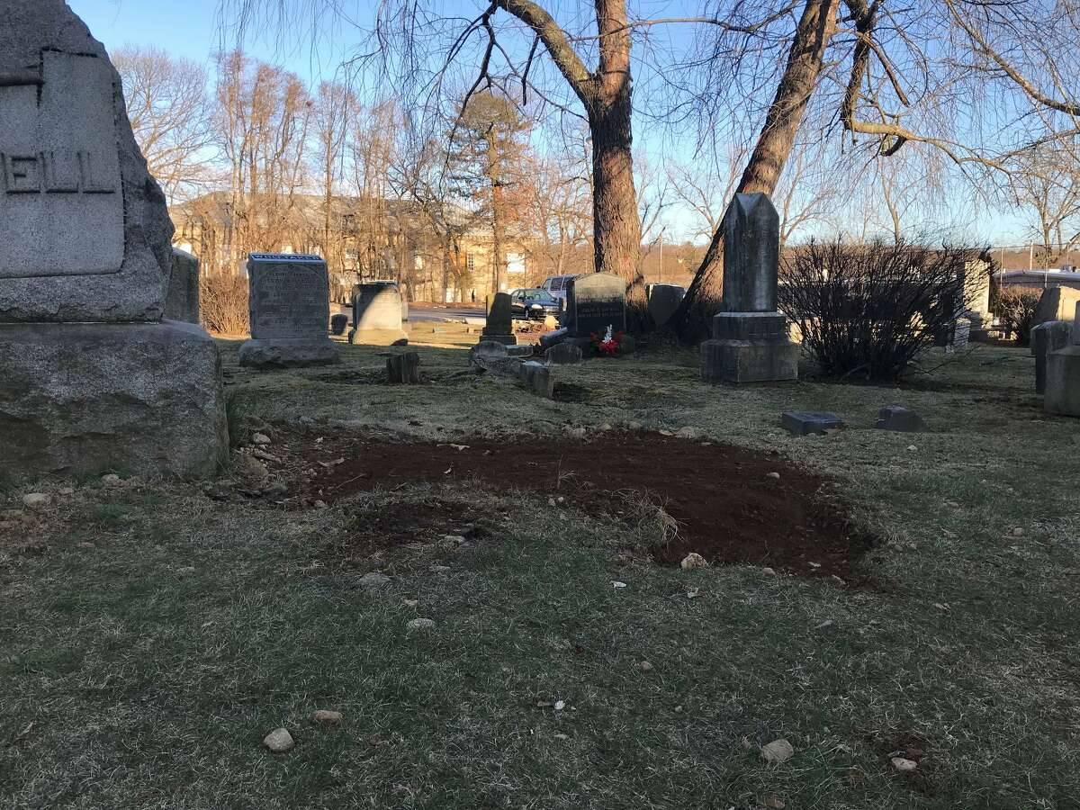 A mound of fresh dirt in the foreground is where police found human bone fragments earlier this week in a near-forgotten cemetery in Springdale.
