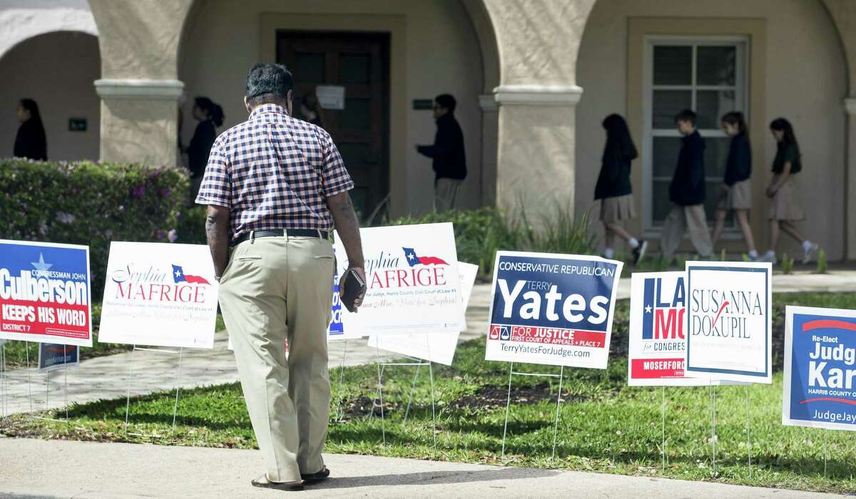 A voter stops to look at primary election signs outside the polling place at St. Anne's Catholic Church on Tuesday, March 6, 2018, in Houston. (Brett Coomer /Houston Chronicle via AP)
