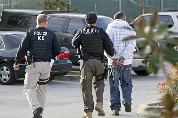 FILE - In this March 30, 2012 file photo, Immigration and Customs Enforcement (ICE) agents take a suspect into custody as part of a nationwide immigration sweep in Chula Vista, Calif. People arrested by deportation officers increasingly have no criminal backgrounds, according to figures released Friday, Feb. 23, 2018, reflecting the Trump administration's commitment to cast a wider net. (AP Photo/Gregory Bull, File)