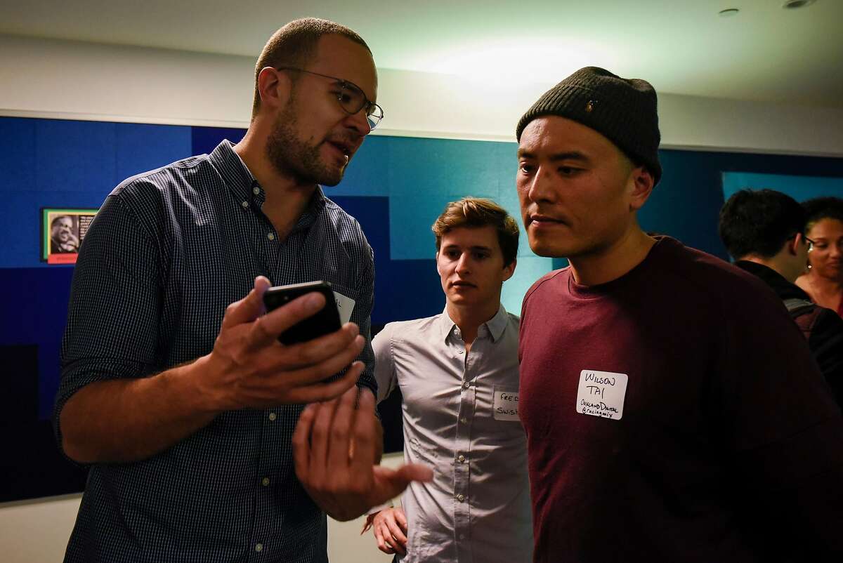 Kahlil Trocome, left, and Fred Bidot, center, show Wilson Tai their Swishh App during a monthly First Friday mixer for Oakland tech entrepreneurs held at the Kapor Center for Social Impact in Oakland, Calif., on Friday February 2, 2018.