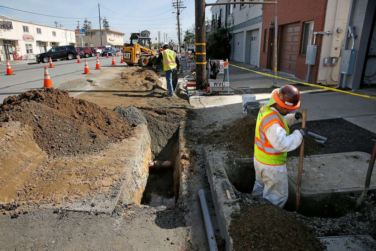 Workers dig ditches that will carry the P.G. & E. power lines underground along Old Country Rd. near Harbor Way, with plans on removing the overhead power poles in six weeks, in Belmont, Calif., on Tues. Mar. 6, 2018.