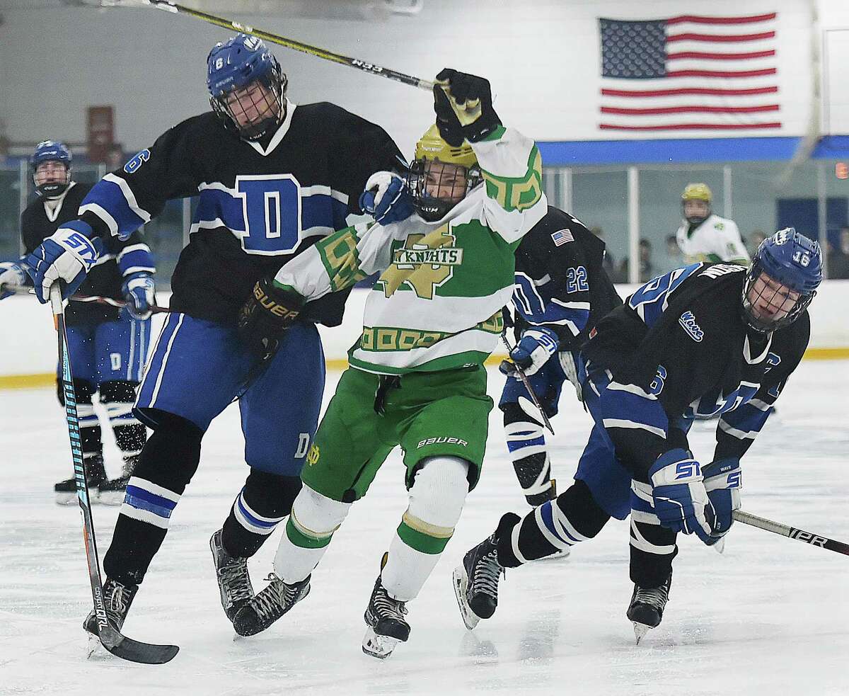 Darien's James Gregory (6) collide and captain William Dickson (16) with Notre Dame-West Haven's Chris Hibson chasing down a loose puck, Thursday, March 8, 2018, in the Division 1 first-round game at Bennett Rink in West Haven. Darien won, 3-2, in overtime.