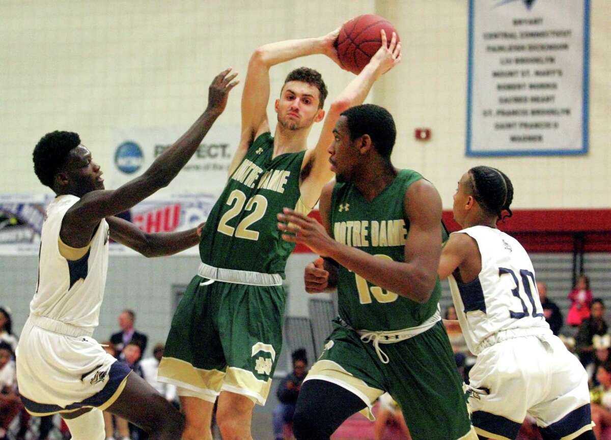 Notre Dame of West Haven's Connor Raines (22) looks to pass the ball over to teammate Mike Brooks (13) as he is pressured by Notre Dame of Fairfield's Damion Medwinter (1) at left, and Tyler Bourne (30) during Division I state basketball tournament action at Sacred Heart UNiversity in Fairfield, Conn., on Thursday Mar. 8, 2018.