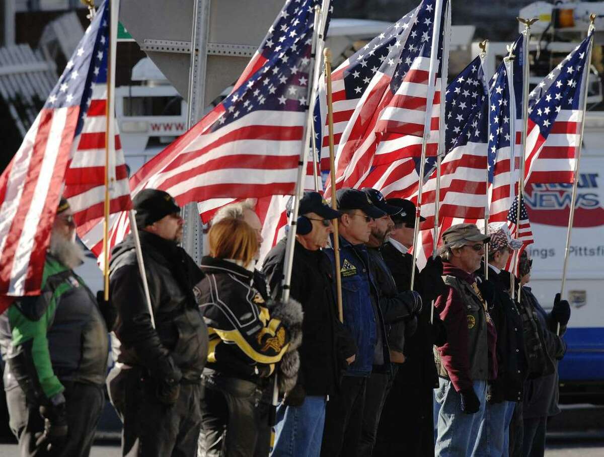 Members of the Patriot Guard Riders on Tuesday line the sidewalk holding flags outside Reach Out Fellowship church in Colonie for the funeral of Army Staff Sgt. Amy Seyboth Tirador, who died in Iraq. (Paul Buckowski / Times Union)