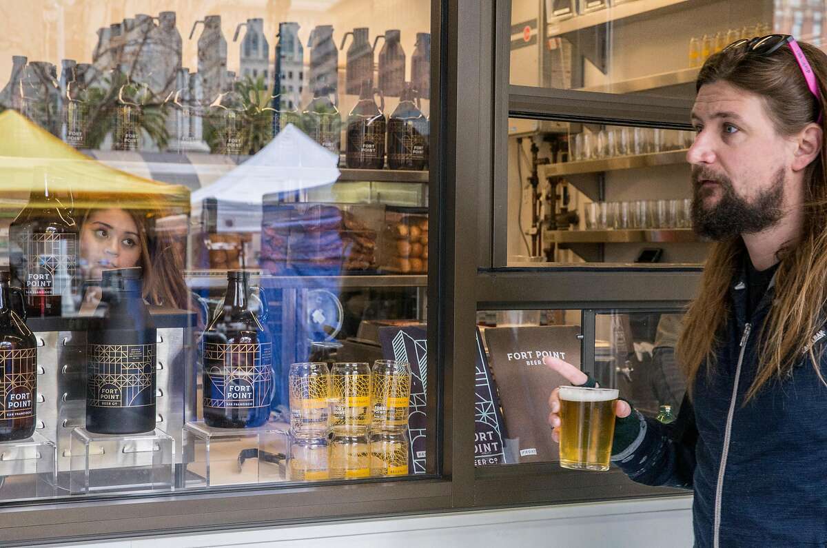 A man walks with beer in hand from the Fort Point walk-up window outside the Ferry Building Saturday, March 3, 2018 in San Francisco, Calif.