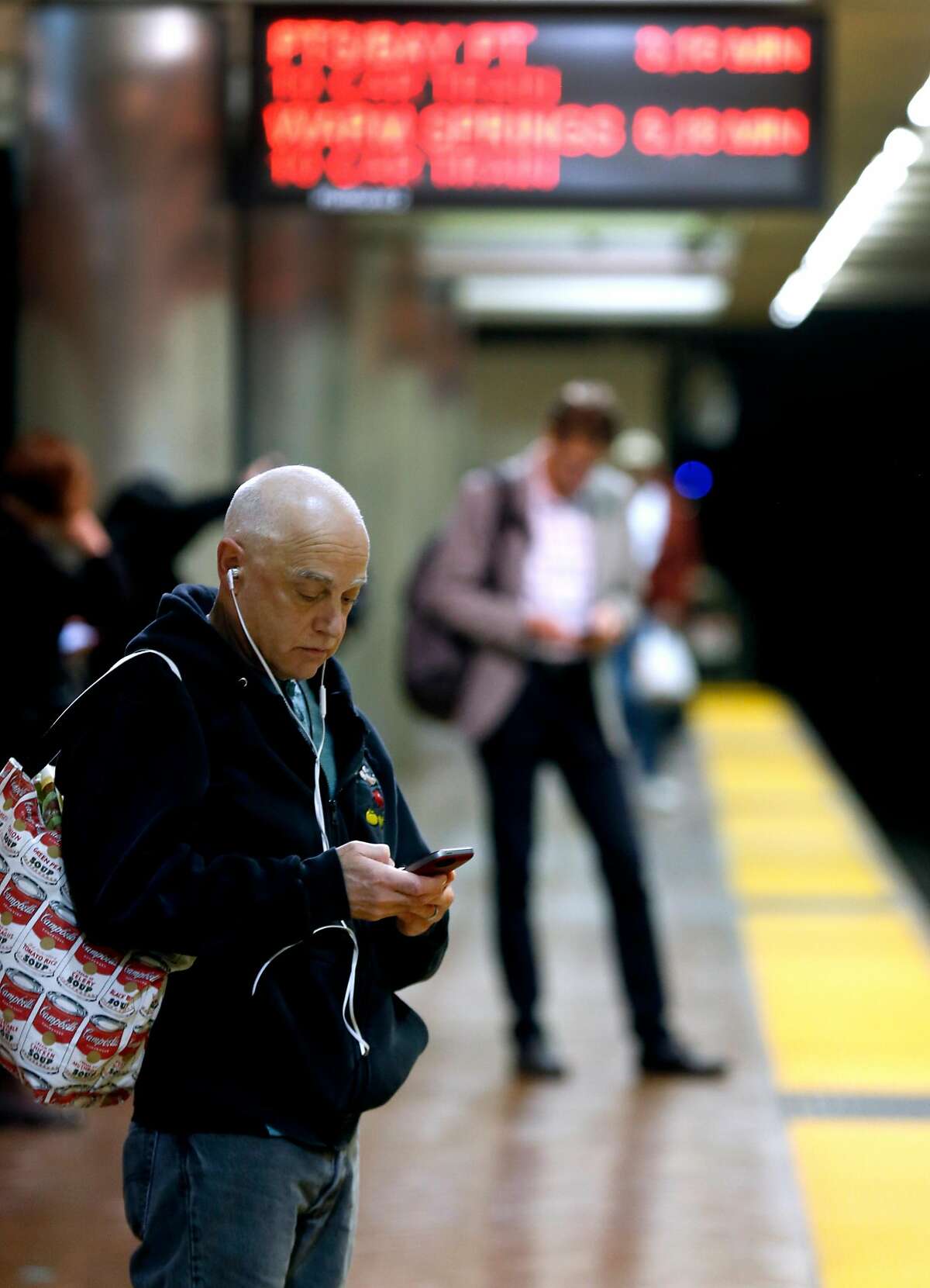 Commuters use their mobile phones while waiting to board eastbound trains at the Powell Street BART station in San Francisco, Calif. on Wednesday, March 7, 2018. BART is about to award a contract to provide wi-fi connectivity in all of its stations and trains.