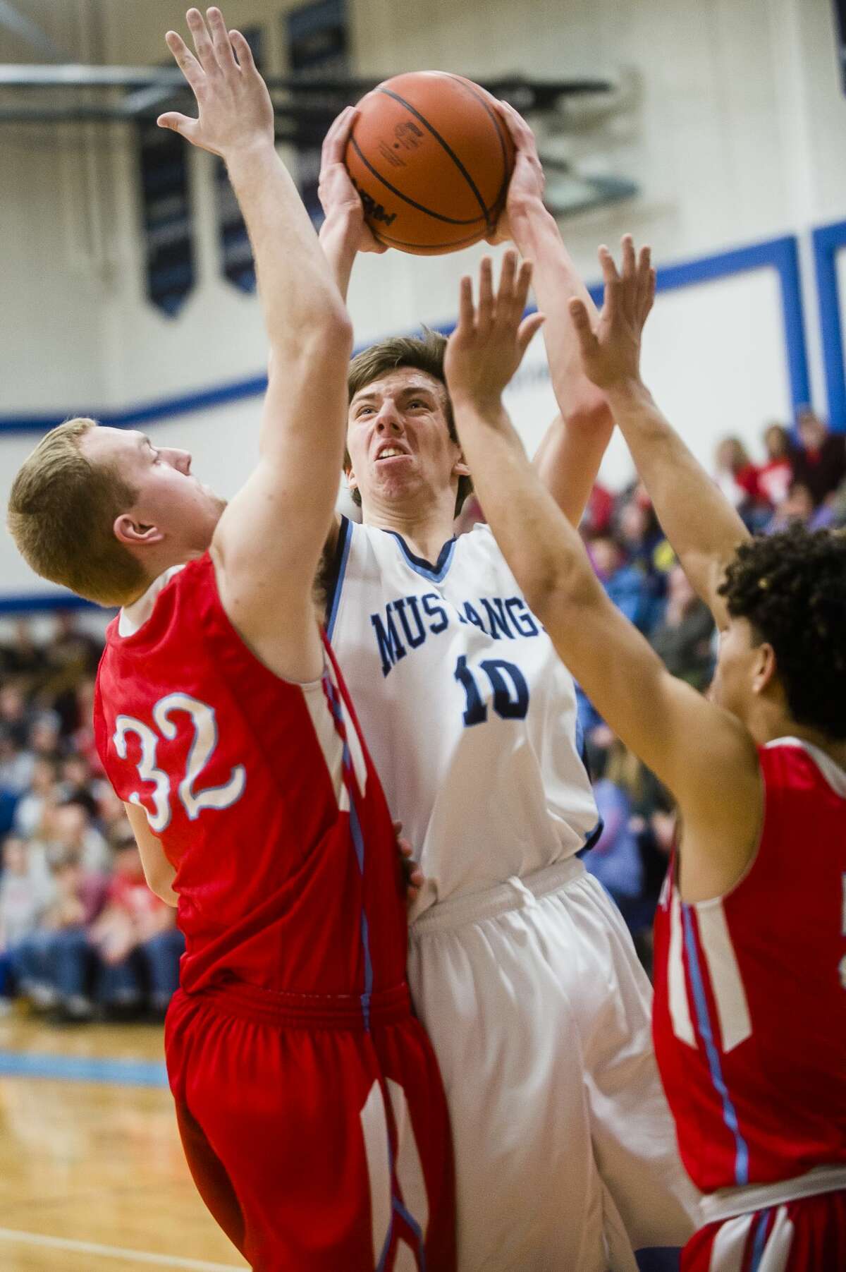 Meridian senior Hunter Wishowski takes a shot while Beaverton junior Logan Gerow, left, and senior Nate Taylor, right, guard him during their district championship game on Friday, March 9, 2018 at Meridian High School. (Katy Kildee/kkildee@mdn.net)