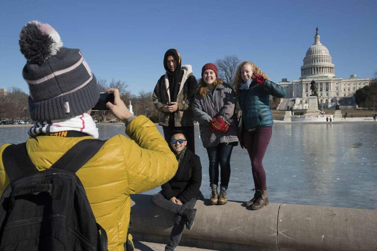 Visitors pose for photos beside the frozen Reflecting Pool at the Capitol.