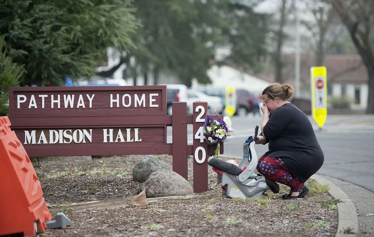 A woman who declined to give her name cries after placing flowers at a sign at the Veterans Home of California, the morning after a hostage situation in Yountville, Calif., on Saturday, March 10, 2018. A daylong siege at The Pathway Home ended Friday evening with the discovery of four bodies, including the gunman, identified as Albert Wong, a former Army rifleman who served a year in Afghanistan in 2011-2012. (AP Photo/Josh Edelson)