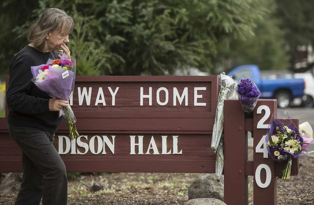 A woman leaves a bouquet of flowers in memorial following the deadly shooting of three female Pathway Home employees by a former resident at Yountville Veterans Home of California Saturday, March 10, 2018 in Yountville, Calif.