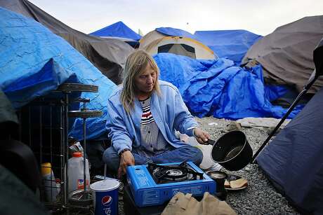 Samantha Howell warms makes some coffee as she prepares dinner at Last Chance Village on Wednesday,  March 7, 2018, in Santa Rosa, Calif.  Howell says she is part of security at Last Chance Village.