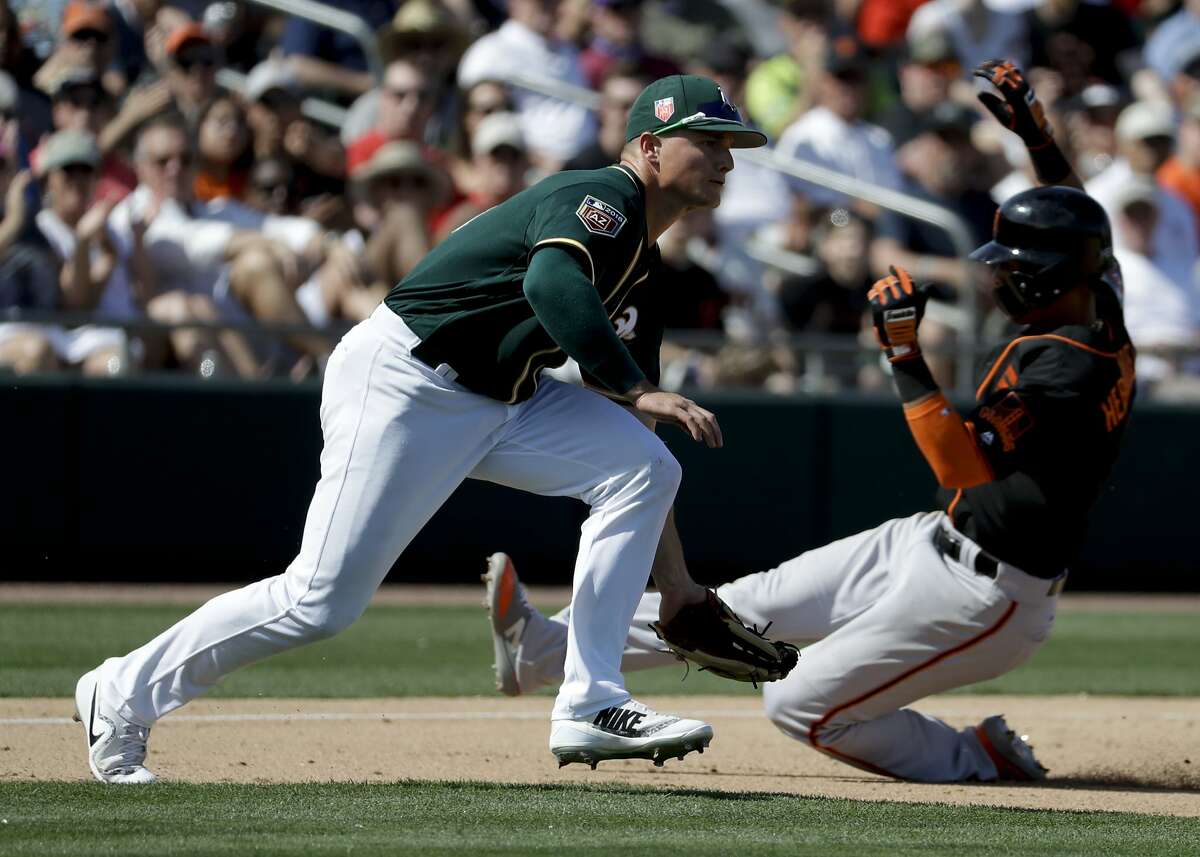 San Francisco Giants' Gorkys Hernandez, right, is safe at third past Oakland Athletics third baseman Matt Chapman on a double by Joe Panik during the fifth inning of a spring baseball game in Mesa, Ariz., Monday, March 12, 2018. (AP Photo/Chris Carlson)