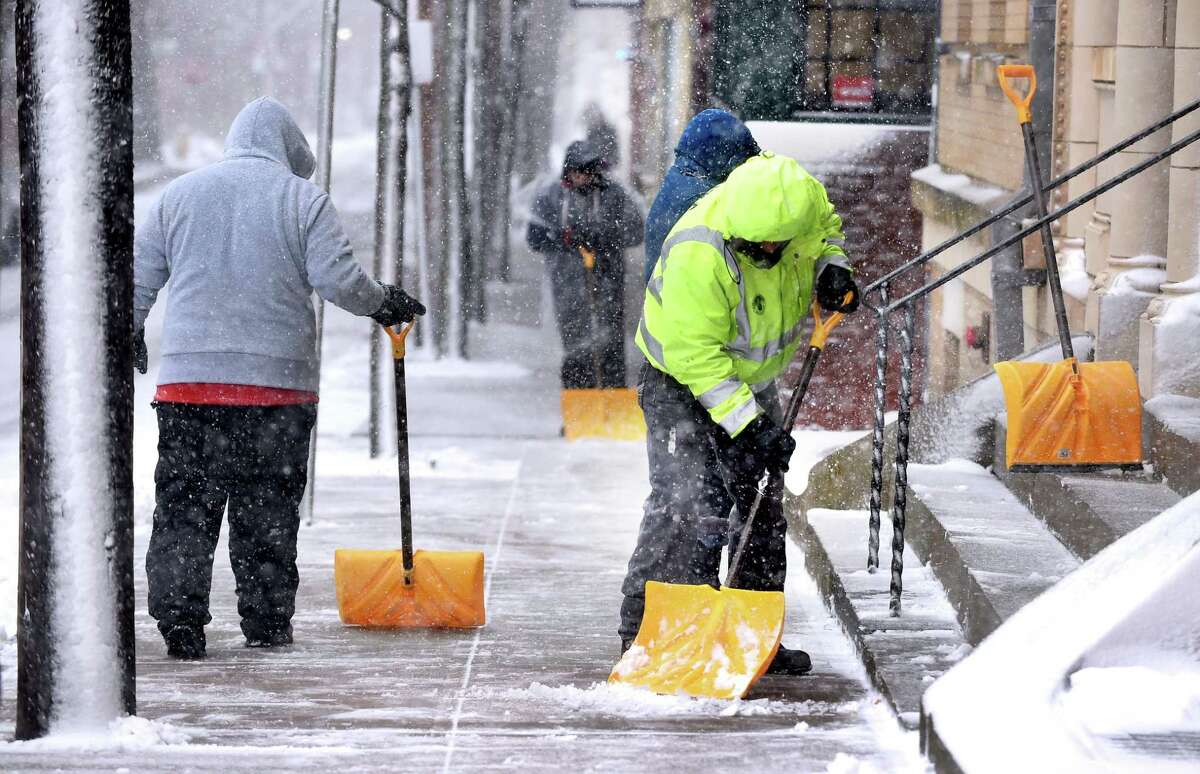 A crew of shovelers clears the snow on a sidewalk on Wall St. in New Haven on March 13, 2018.