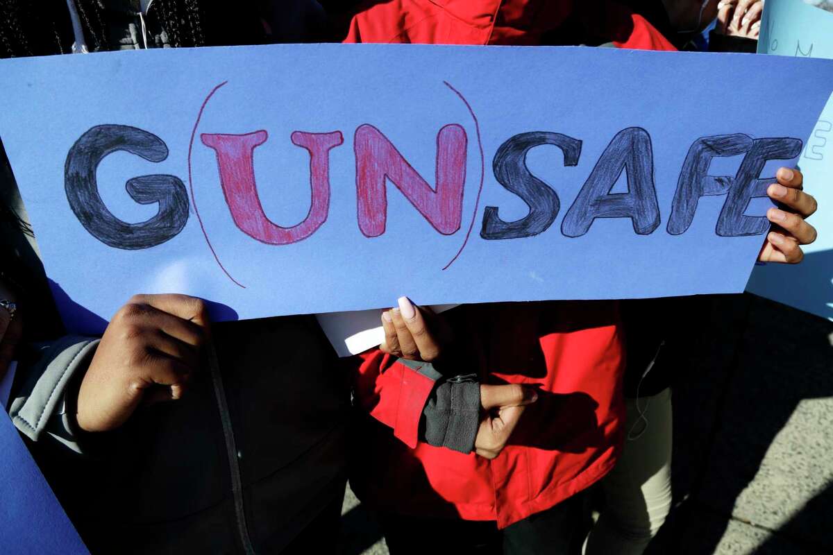 James Ferris High School freshmen Diamond Bryant, left, and James Williams interlock arms while holding a sign during a student walkout, Wednesday, March 14, 2018, in Jersey City, N.J. Students across the country participate in walkouts Wednesday to protest gun violence, one month after the deadly shooting inside a high school in Parkland, Fla.