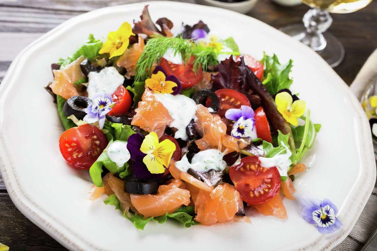 Fresh salad with smoked salmon, black olives, cherry tomatoes and edible flowers.