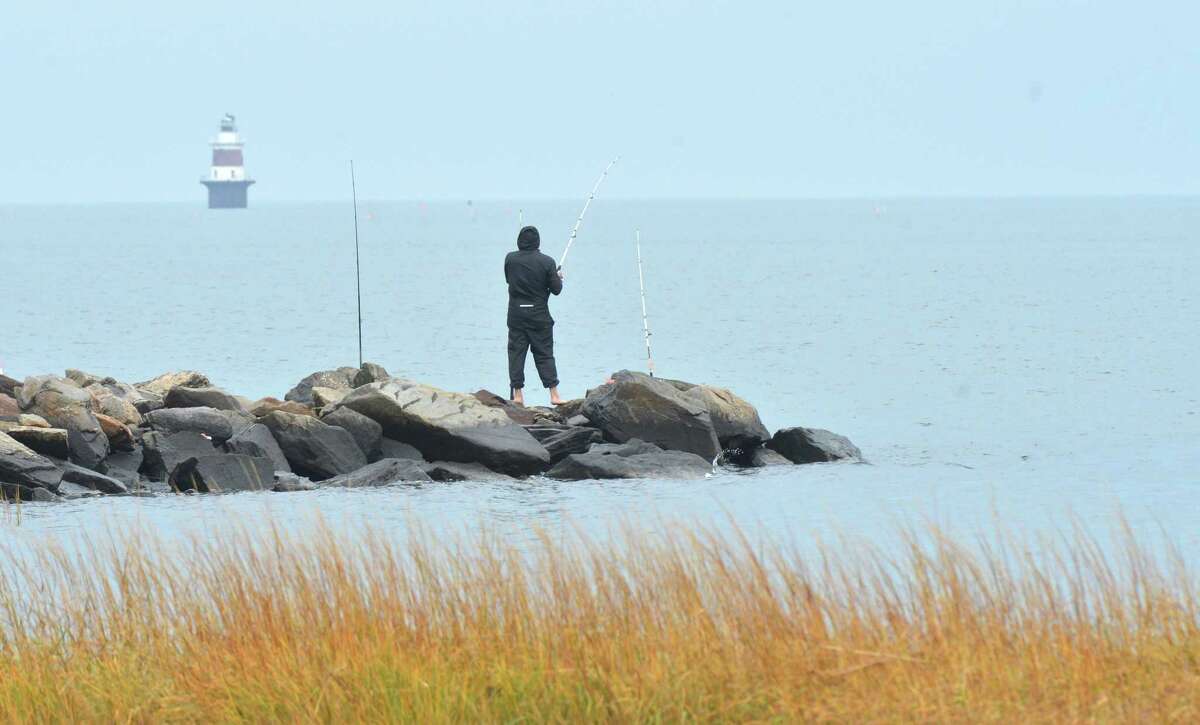 Anglers cast their lines while fishing off a rock jetty with Pecks Ledge Lighthouse in the distance at Calf Pasture Beach in Norwalk in November.