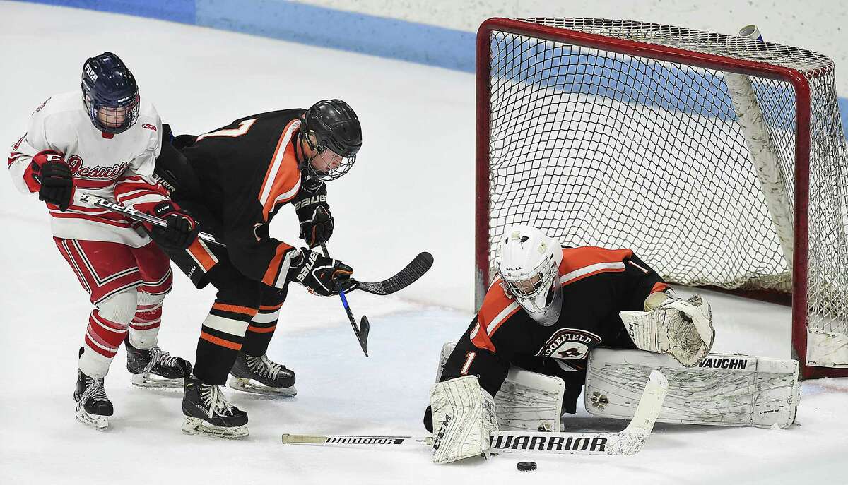 Fairfield Prep Calyb Reeves battles Ridgefield senior Liam Galloway at the goal as junior goalie Sean Gordon defends in the CIAC Division I hockey semifinal matchup, Wednesday, March 14, 2018, at Ingalls Rink in New Haven. Prep won, 4-1.