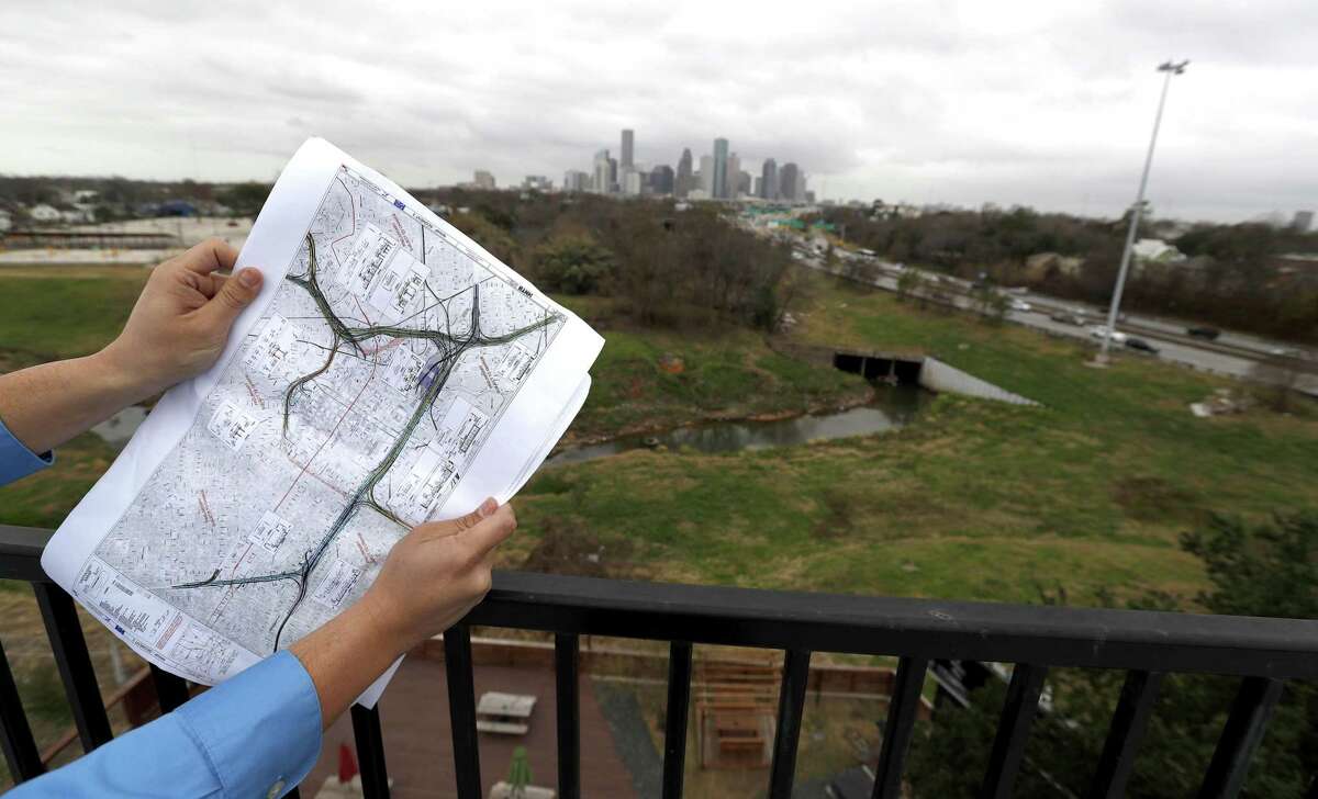 Jorge Bustamante with the Greater Northside Management District holds up a map while standing in The Raven's Tower, overlooking the Near Northside area potentially impacted by widening Interstate 45.