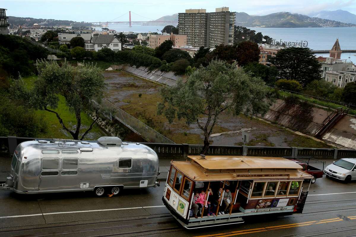 A cable car rides along Hyde Street next to the Francisco Reservoir, Tuesday, March 13, 2018, in San Francisco, Calif. The site is located in the Russian Hill neighborhood at Francisco Street and Hyde Street.