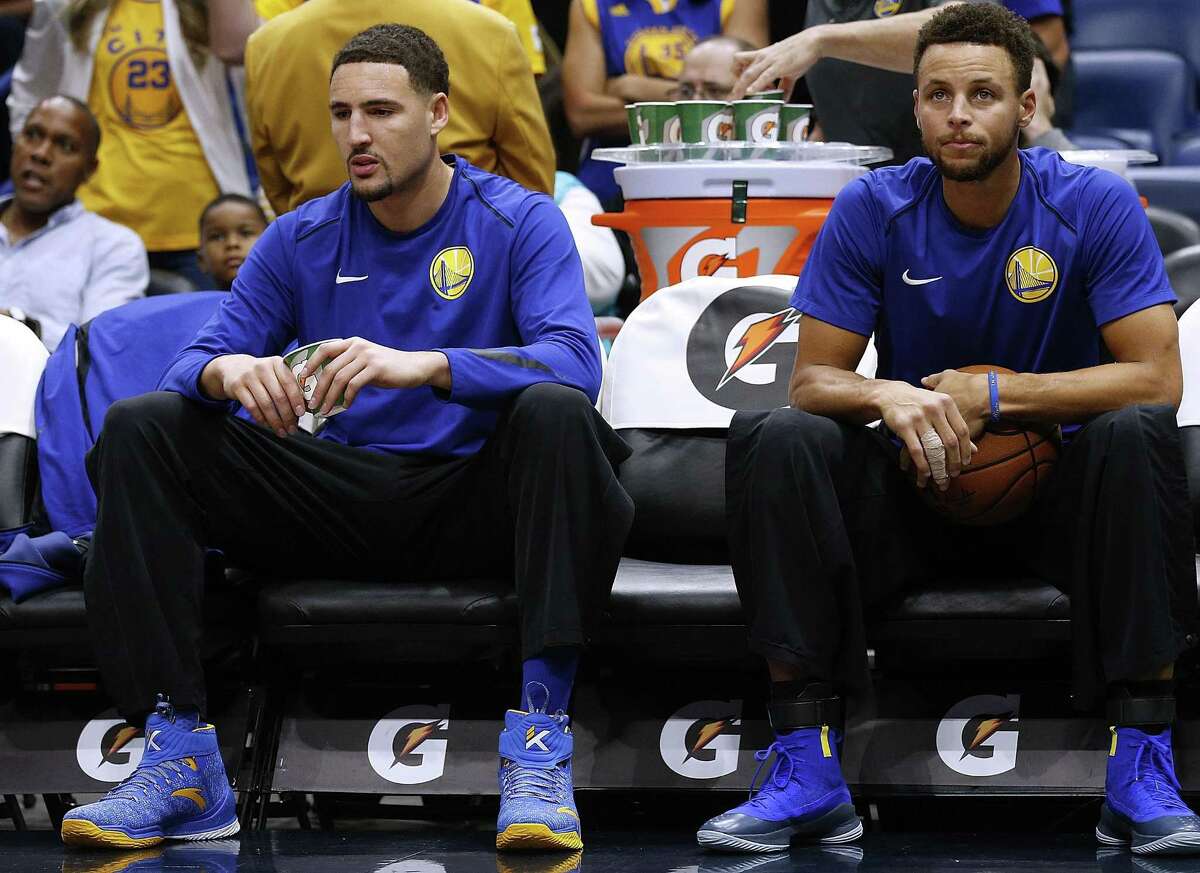 Stephen Curry #30 of the Golden State Warriors (R) and Klay Thompson #11 sit on the bench before a game against the New Orleans Pelicans at the Smoothie King Center on December 4, 2017 in New Orleans, Louisiana.