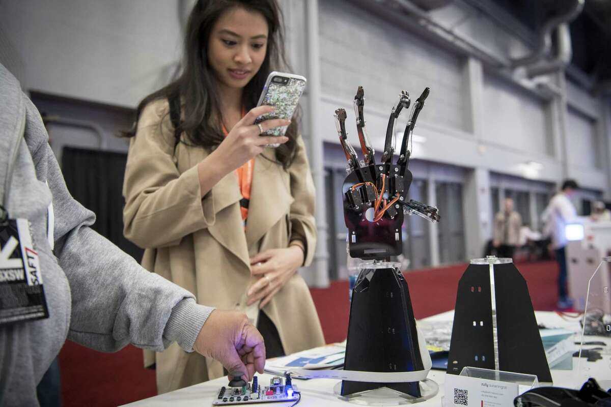 An attendee takes a photograph of a Saft7 Robotics hand at the South By Southwest (SXSW) conference in Austin, Texas, U.S., on Tuesday, March 13, 2018. Amid the raucous parties and speed networking at the annual festival that draws people from technology, film, and music to Austin, Texas, there will be some soul searching about gender discrimination, sexual harassment and how to fix the broken workplace culture. Photographer: David Paul Morris/Bloomberg