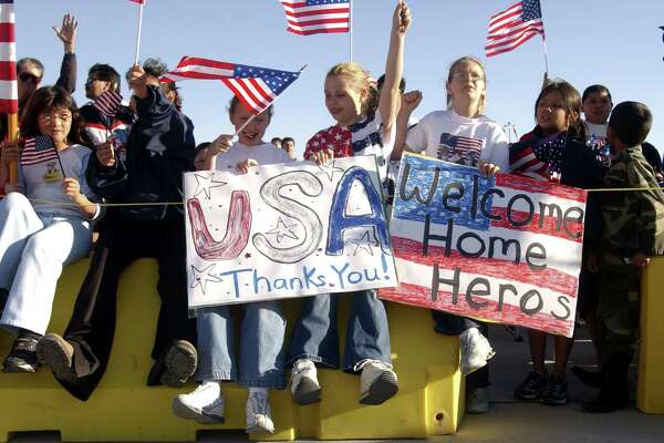 Youngsters cheer and hold signs as they wait on the tarmac for seven prisoners of war to return home to Ft. Bliss in El Paso, TX, Saturday evening, April 19, 2003.
