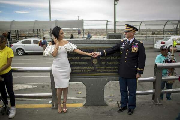 Retired chief warrant officer Dave Williams and his bride, Lourdes Carreón, stand on opposite sides of the U.S. -  Mexico border for a photo in Ciudad Juarez.