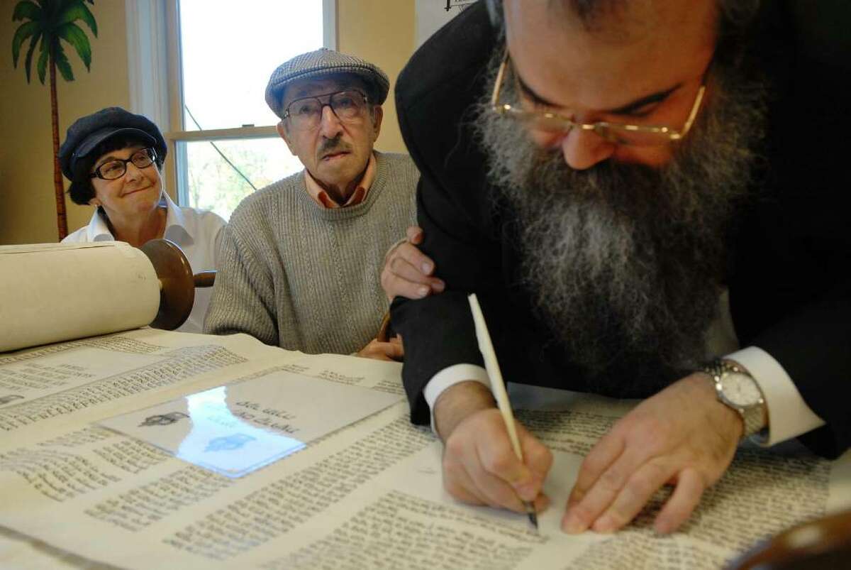 Joan and Moshe Sinai, at left, take part in a dedication along with Rabbi Feitel Levin, a scribe from Brooklyn, at Maimonides Hebrew Day School in Albany during a Torah scroll dedication on Sunday, Oct. 25, 2009. Moshe Sinai, 84, was a 13-year-old Hungarian in the late 1930s when he was shipped out of Vienna, Austria, as part of the Kindertransports, a rescue operation to send Jewish children to Britain. (Paul Buckowski / Times Union)