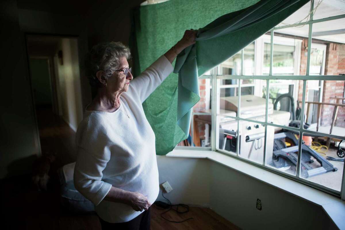 Gloria Bullock, 78, lifts her table linen substituting her flood damaged curtains at her home, Monday, March 12, 2018, in Bear Creek Village. Bullock and her husband, with the help of the community has been working hard trying to get their home functional after it got flooded.