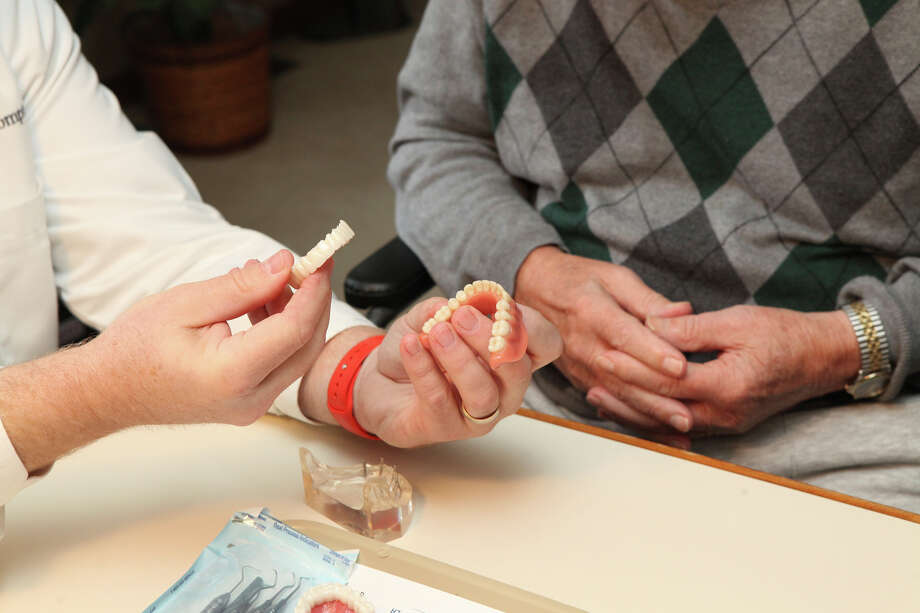 FILE- In this Nov. 9, 2016, file photo, Dr. Eric Compton makes a house call with patient Lester Meyer and his wife Rosemary to consult on dental implants in Munster, Ind. Dental implants are increasingly being used to replace missing or failing teeth instead of dentures or bridges, which can be uncomfortable and hasten further deterioration. Experts say dental implants, usually titanium screws inserted into jawbone and capped with a permanent crown, are long-lasting and the best option for most people. (Tony V. Martin/The Times via AP, File) Photo: Tony V. Martin / © 2016