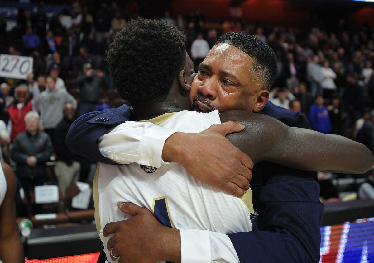 With tears in his eyes, Notre Dame of Fairfield coach Chris Watts hugs player Damion Medwinter following the Lancers’ 65-60 victory over Sacred Heart in the Division I championship on Sunday at the Mohegan Sun Arena in Montville.