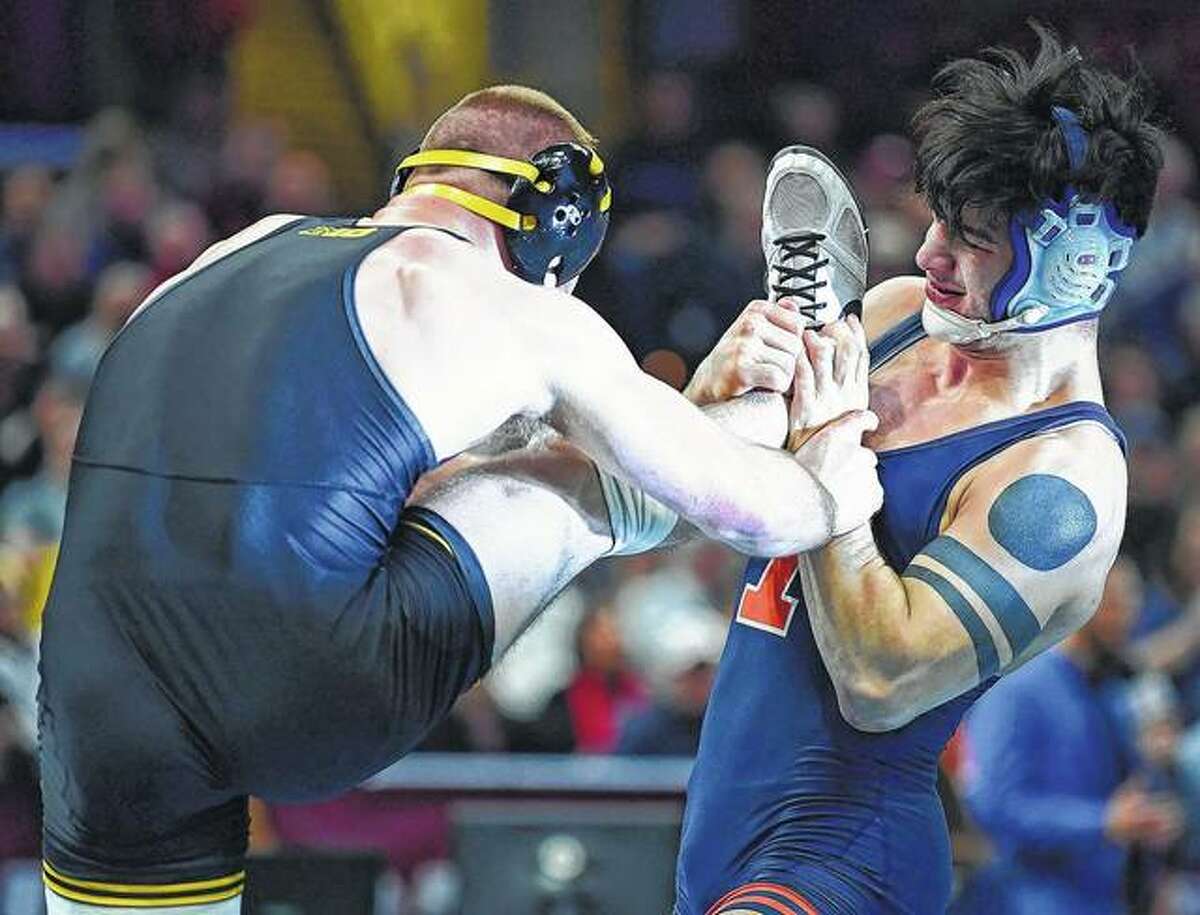 Illinois’ Isaiah Martinez holds the leg of Iowa’s Alex Marinelli during the 165-pound bout at the NCAA Division I wrestling championships in Cleveland. Martinez won the match.