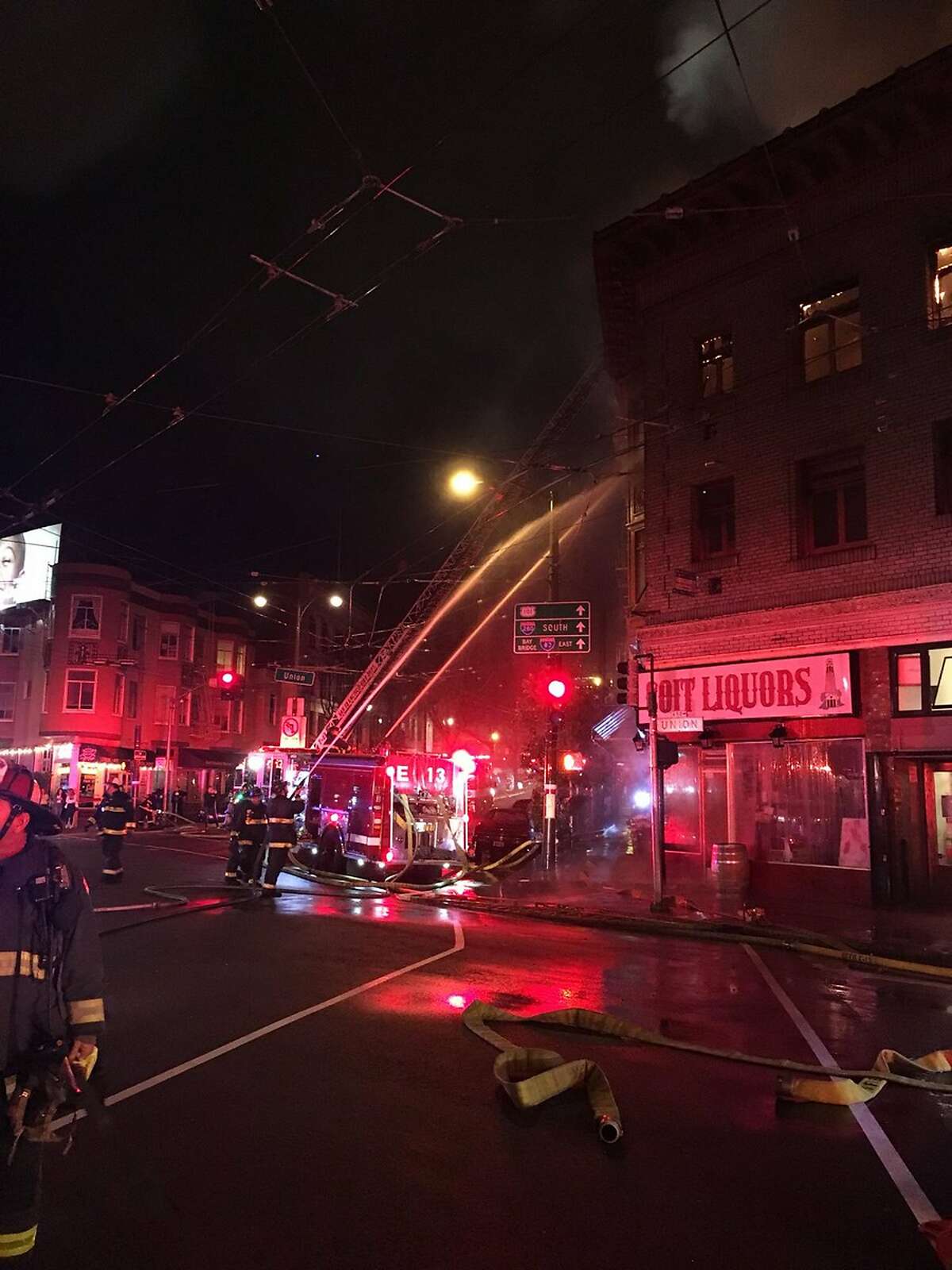 In this Saturday, March 17, 2018, photo released by the San Francisco Fire, firefighters contain a blaze on a building in the heart of San Francisco's North Beach district in San Francisco. San Francisco Fire authorities are investigating the cause of the massive building blaze that broke out during the thick of St. Patrick's Day celebrations. (San Francisco Fire via AP