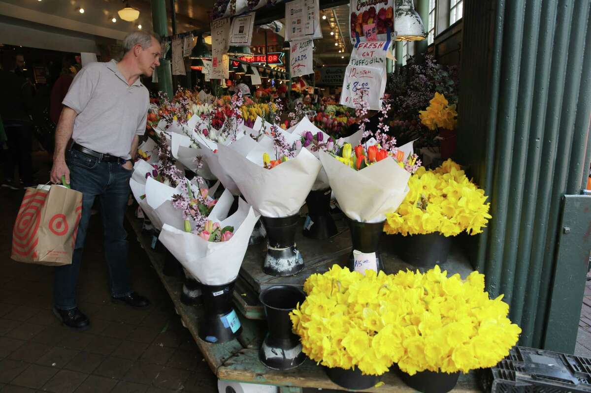 Spring flowers brighten the Pike Place flower market, Tuesday, March 20, 2018. Dozens of volunteers handed out over 9,000 locally grown daffodils to people throughout downtown Seattle, Tuesday afternoon, to celebrate the first day of spring. This is the 21st annual Pike Place Market Daffodil Day.