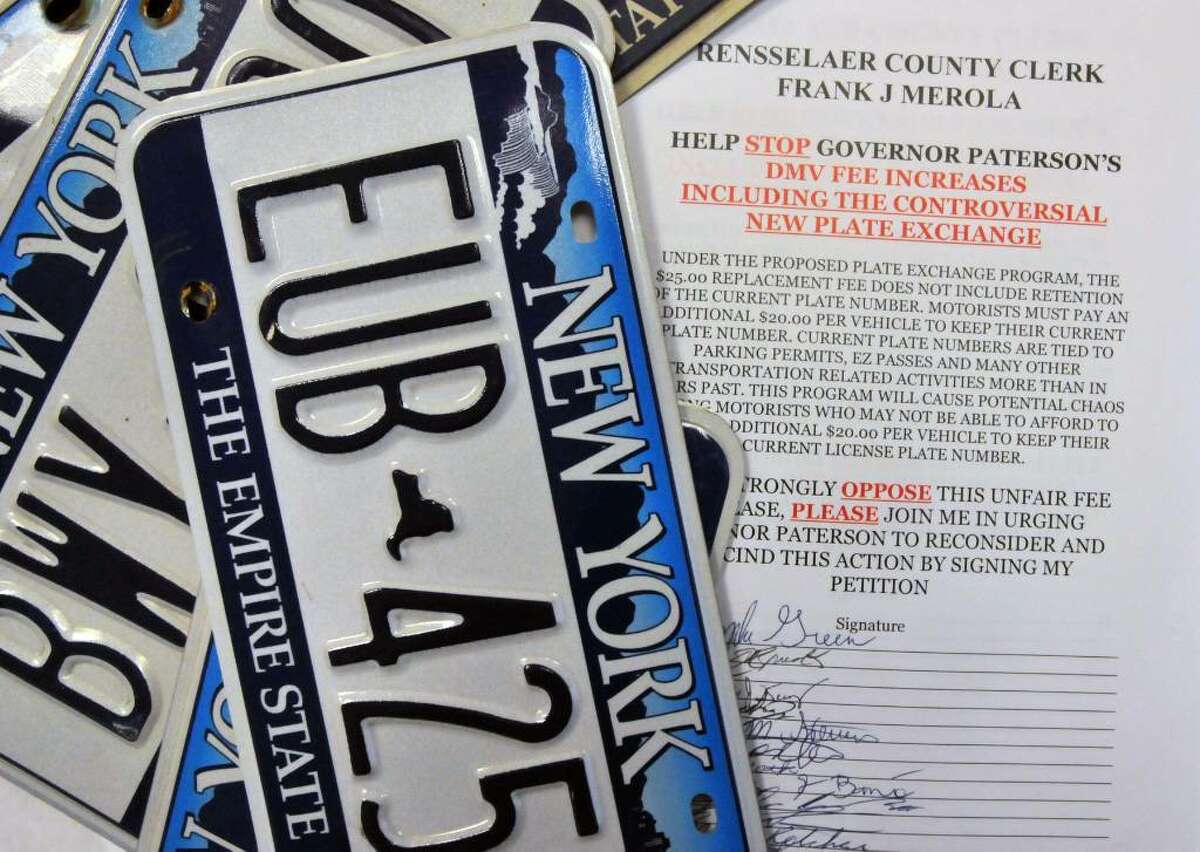 Surrendered state license plates returned in near-pristine condition and petitions against the new $25 license plates are displayed on the desk of Rensselaer County Clerk Frank Merola. (John Carl D'Annibale / Times Union)