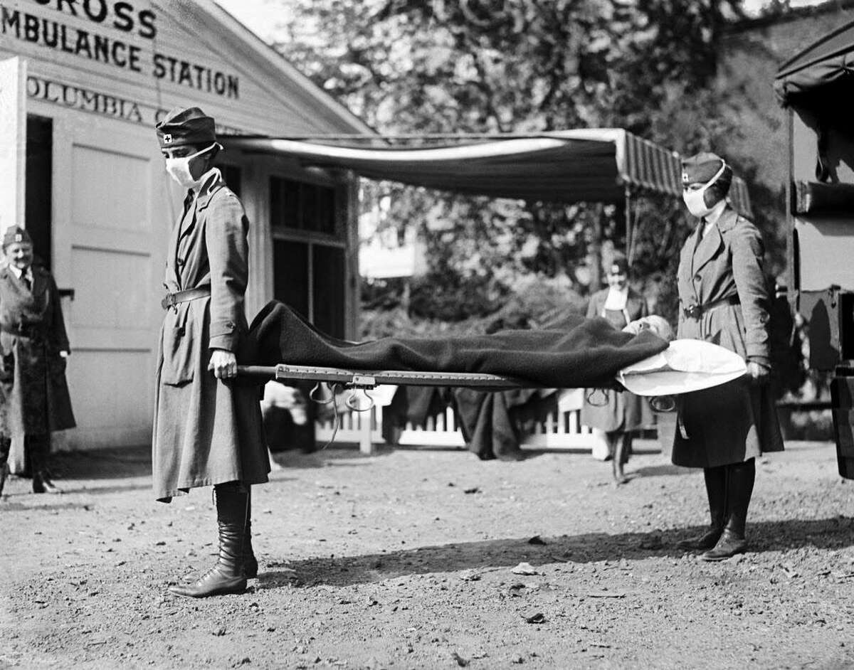 Two Red Cross nurses with a person on a stretcher during a demonstration at the Red Cross Emergency Ambulance Station during the influenza pandemic of 1918-20 in Washington, D.C., 1918.