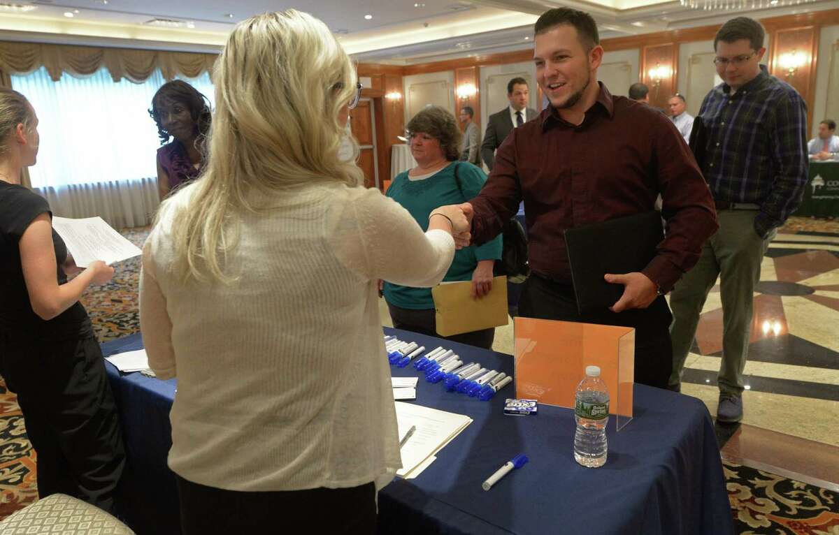 Juliet Gallicano, director of accounting and finance with The Execusearch Group, greets Ryan McNamara during the Fairfield County Job Fair at the Norwalk Inn and Conference Center on Sept. 14, 2017, in Norwalk, Conn.