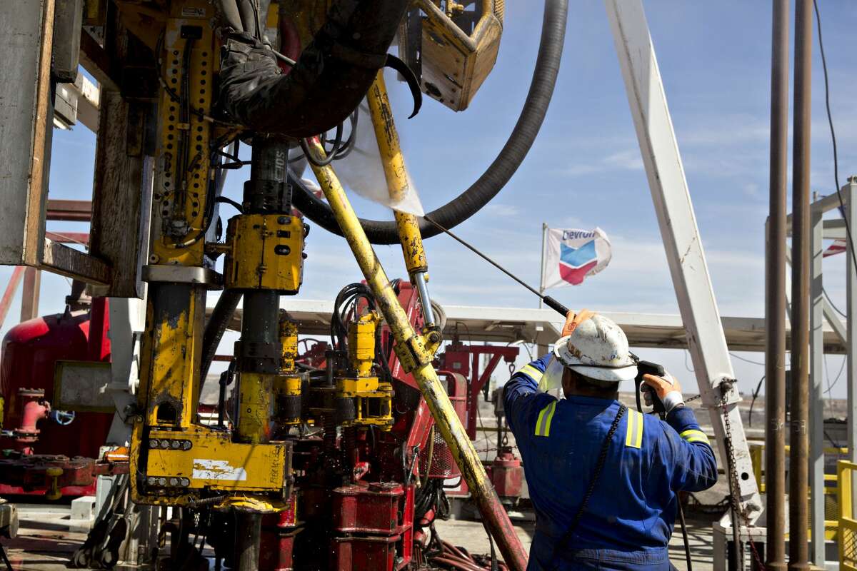 A Nabors Industries Ltd. roughneck uses a power washer to clean the drilling floor of a rig drilling for Chevron Corp. in the Permian Basin near Midland in this file photo. Photographer: Daniel Acker/Bloomberg