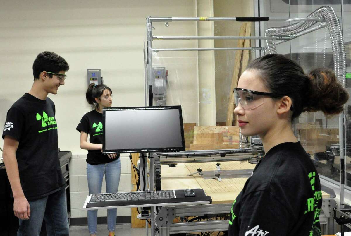 Cinco Ranch High School students Tejas George, Bella Riffle and Kyna McGill stand in front of a high-tech CNC cutting machine at a specal Katy Independent School District Science, Technology, Engineering and Mathematics center to support robotics teams entered in international competitions. The Cinco Ranch students are among 99 teens who joined FIRST Robotics Team 624, known as CRyptonite.