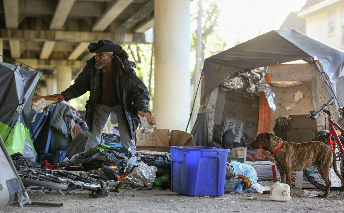 A man, better known as Trampus, finds a pair of shoes he wishes to keep while sorting through his belongings, before city contractors conduct a cleanup of the Wheeler Homeless Encampment located under the US 59 Freeway, between Caroline Street and Almeda Road Friday, March 23, 2018, in Houston.