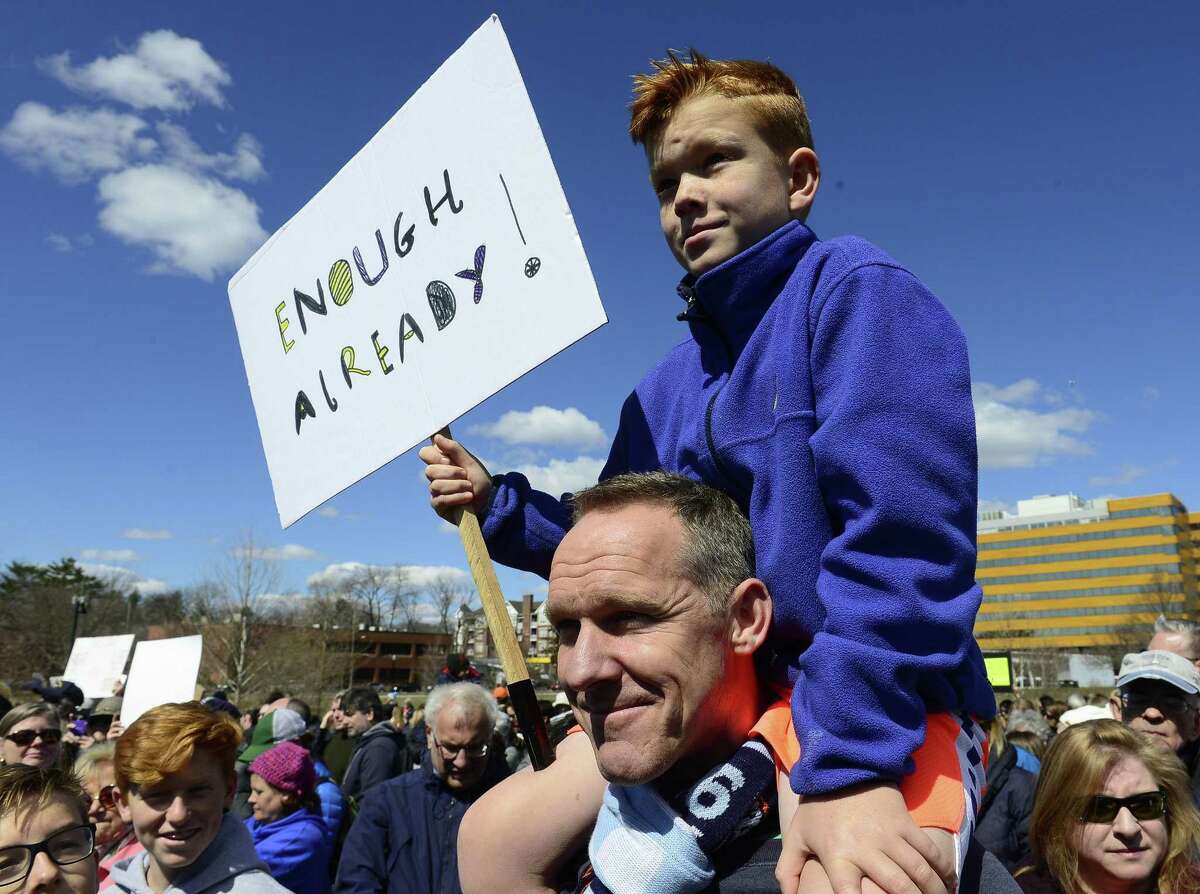 Rudy Hugh-Jones, 8, of Cos Cob sits on the shoulders of his father, Alex during the rally.