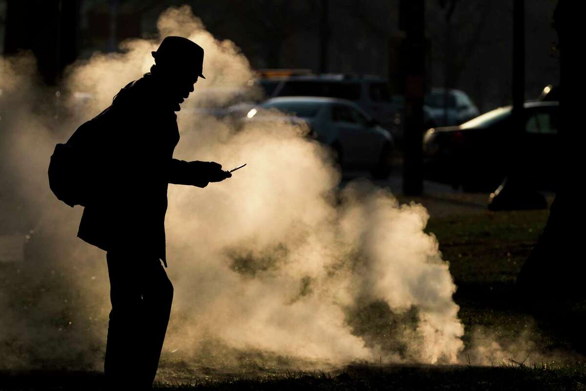 FILE - In this Nov. 30, 2012 file photo, a pedestrian looks at his phone near steam vented from a grate near the Philadelphia Museum of Art on a cold morning in Philadelphia. Every time a person shops online or at a store, loyalty cards linked to phone numbers or email addresses can be linked to other databases that may have location data, home addresses and more. Voting records, job history, credit scores (remember the Equifax hack?) are constantly mixed, matched and traded by companies in ways regulators haven?’t caught up with. (AP Photo/Matt Rourke, File)